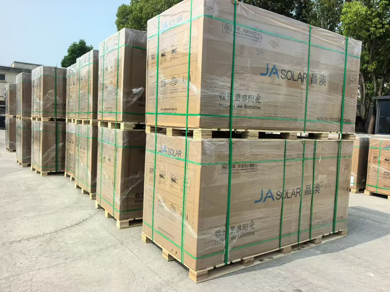 Wrapped JA Solar panel pallets in an outdoor yard