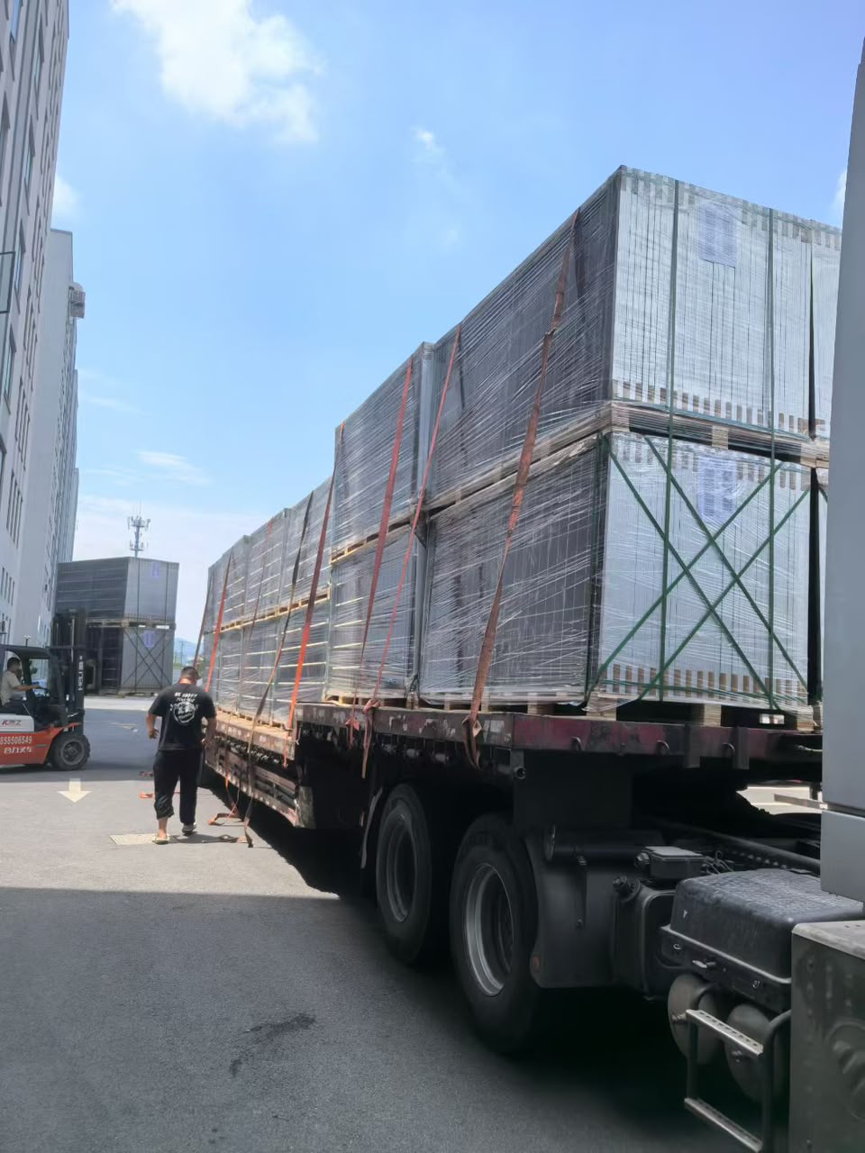 Front view of a truck carrying wrapped and strapped solar panel pallets