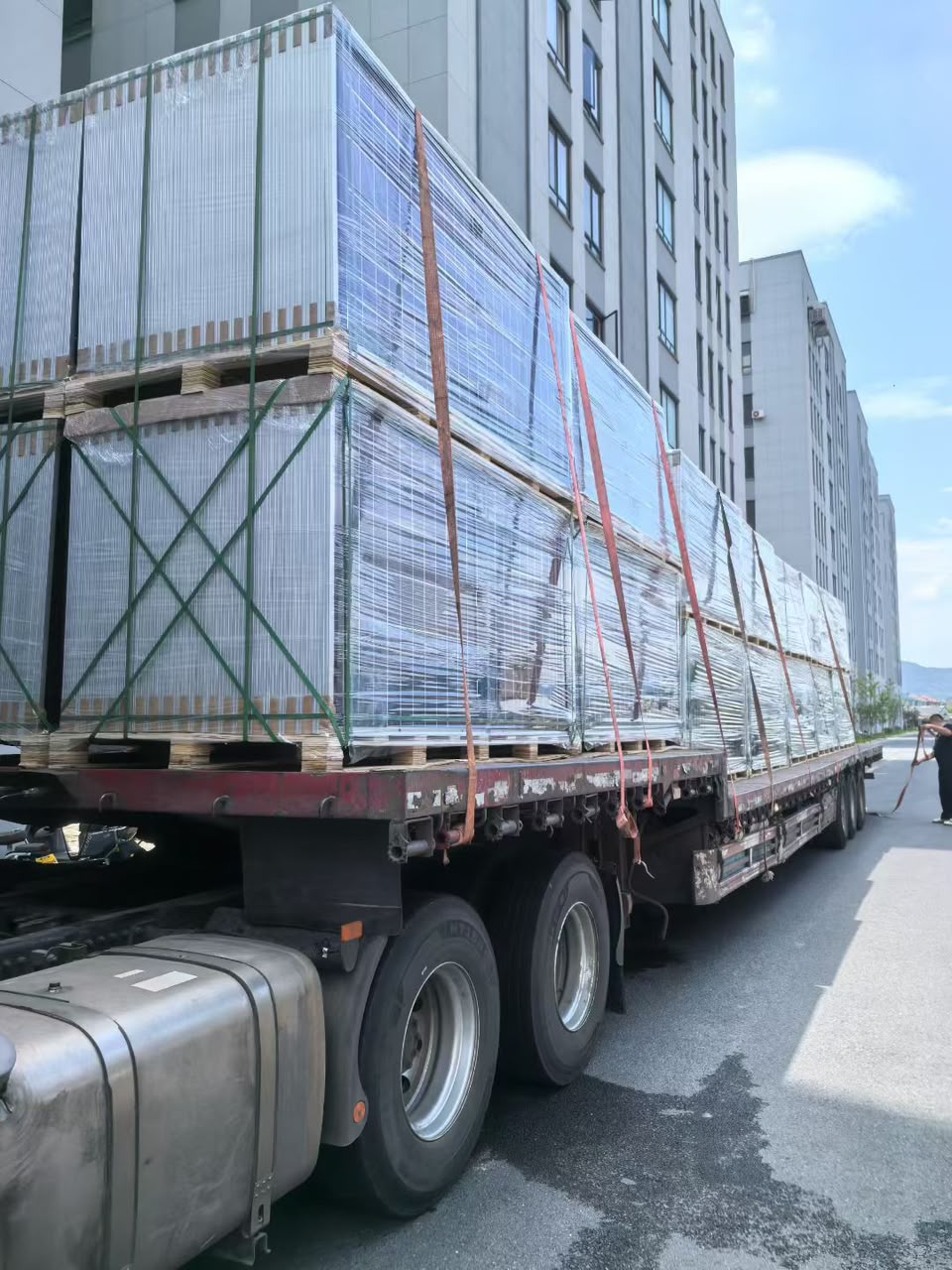 Side view of wrapped solar panel pallets secured on a flatbed truck