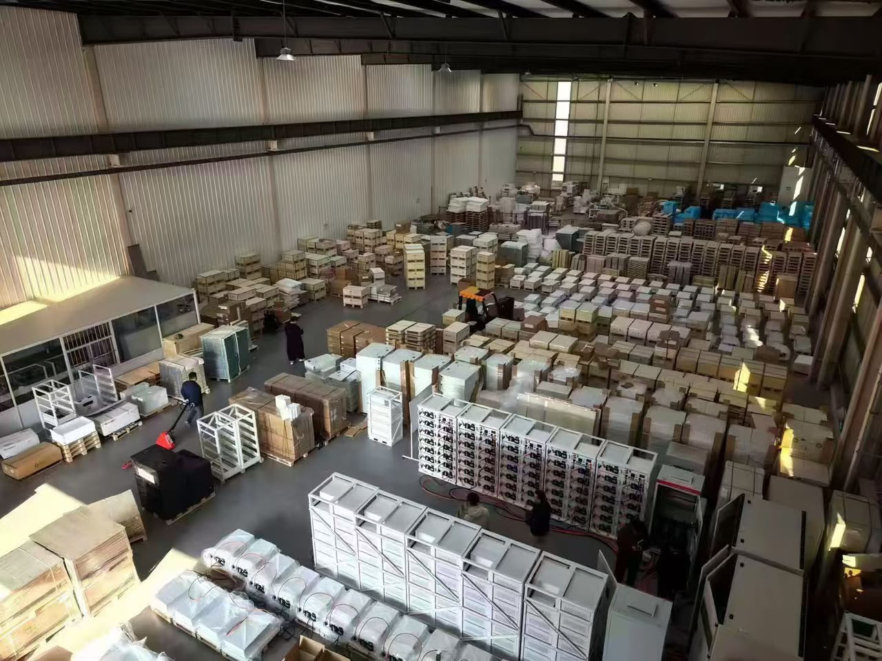 Overhead view of a workshop with battery racks, modules and packaged equipment